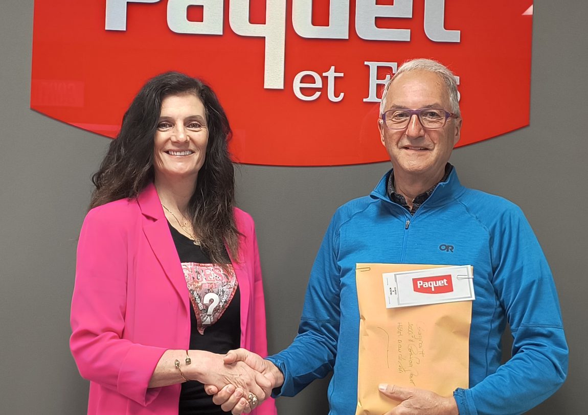 Une femme serre la main d'un homme devant le logo de Paquet et fils.