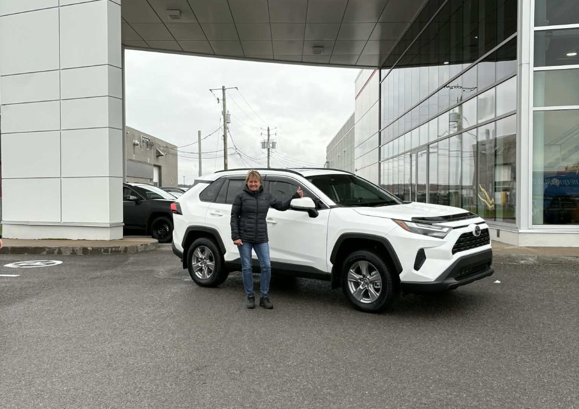 Une femme est debout devant une voiture Toyota