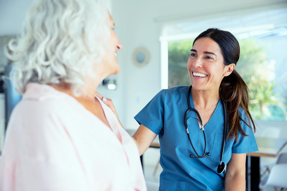 Infirmière souriante échangeant avec une patiente.
