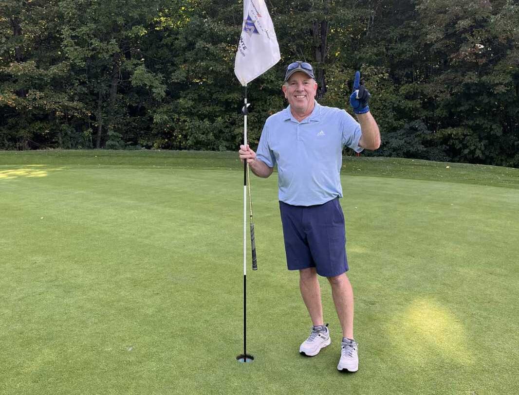 Serge Aubine | Homme en tenue de golf faisant le numéro 1 avec sa main