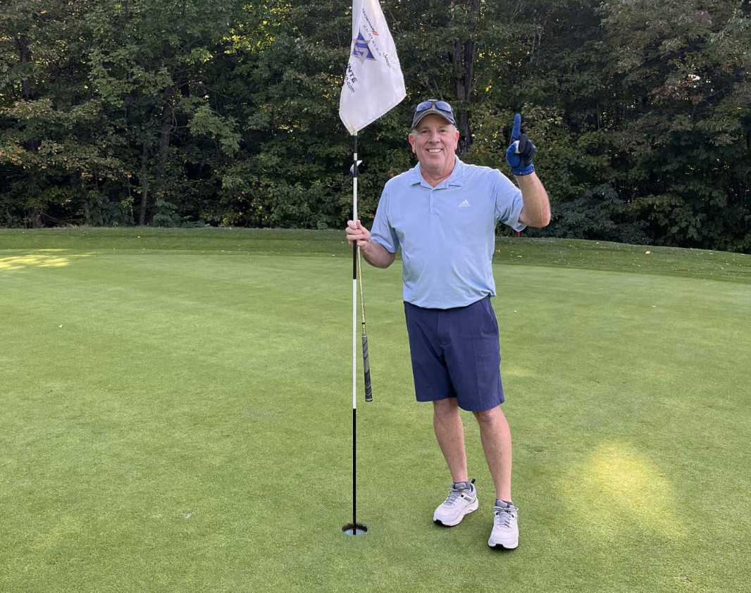 Serge Aubine | Homme en tenue de golf faisant le numéro 1 avec sa main