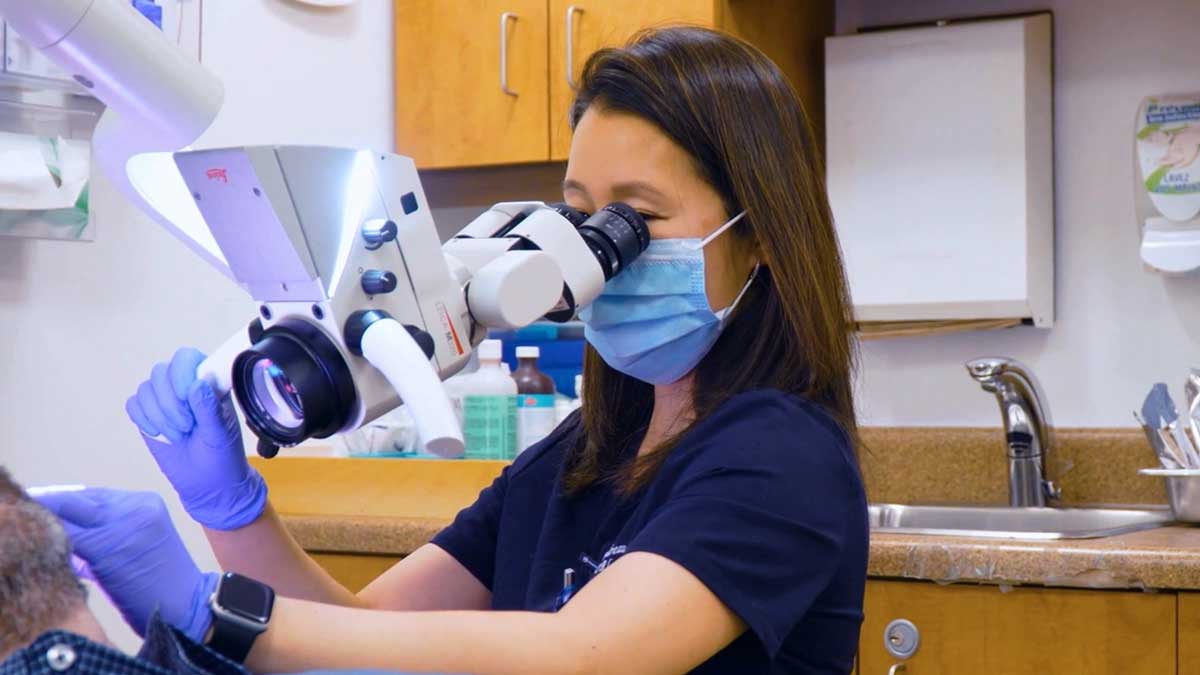 Docteure utilisant un microscope pour observer l'oreille de son patient